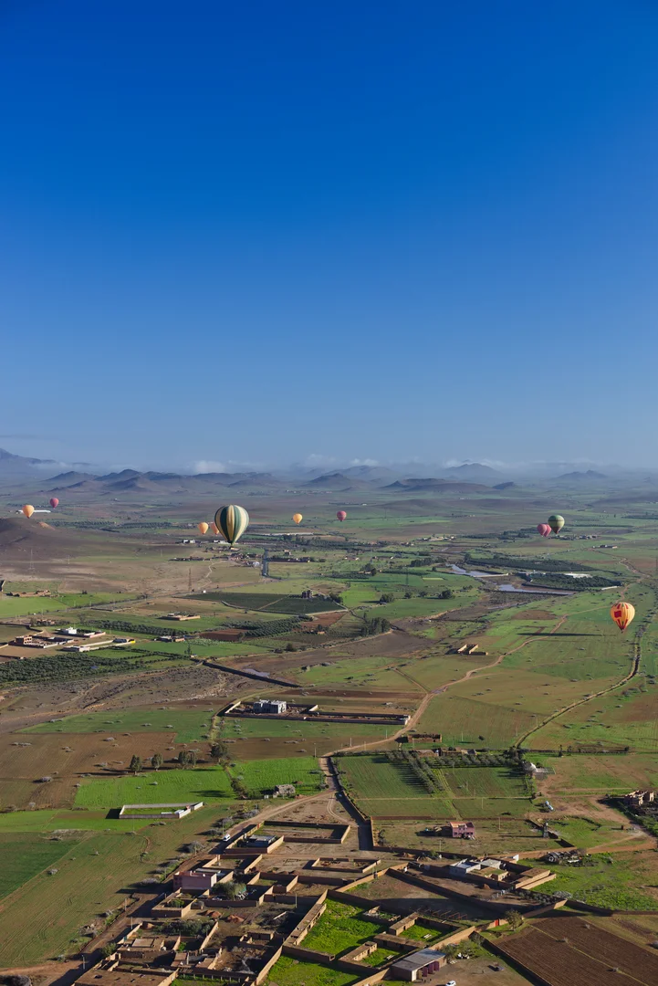 Kleurrijke luchtballonnen zweven boven het droge landschap rond Marrakech